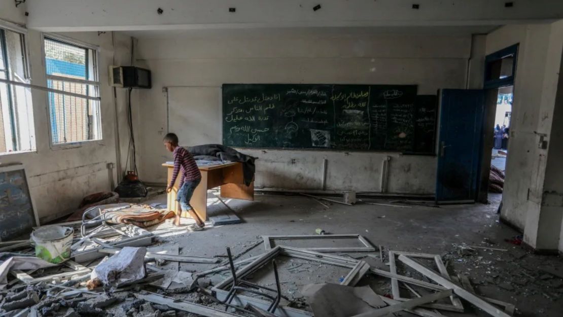 Palestinos y trabajadores de la ONU examinan los refugios improvisados destruidos tras un ataque israelí contra una escuela de la Agencia de la ONU para los refugiados palestinos, en el campo de refugiados de Nuseirat de Deir al-Balah, Gaza, el 15 de julio de 2024.