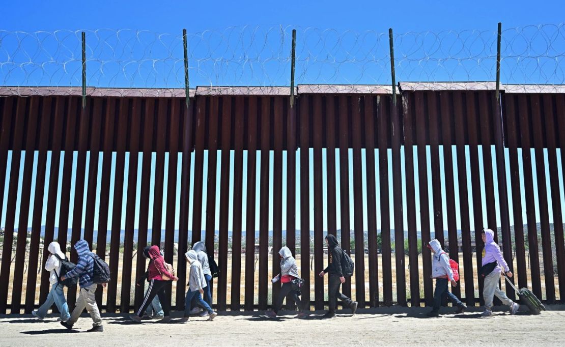 Migrantes caminan por el lado estadounidense del muro fronterizo en Jacumba Hot Springs, California, el 5 de junio, después de cruzar desde México.