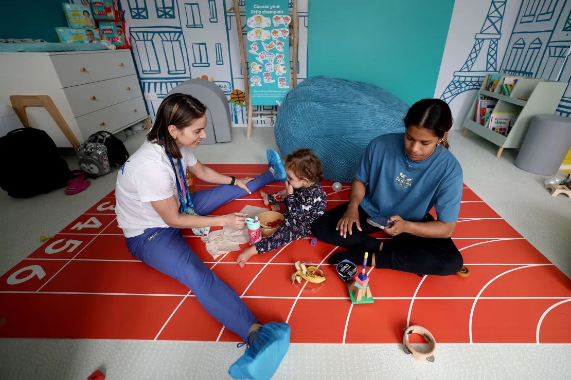 La gimnasta artística panameña Hillary Heron interactúa con su entrenadora Yareimi Vazquez (izq.) y su hija Aitana Vazquez dentro de una habitación infantil en la Villa de los Atletas antes de los Juegos Olímpicos de París.