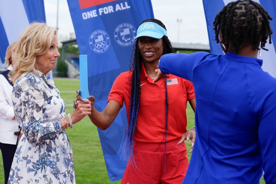 La Primera Dama Jill Biden, a la izquierda, aprende la técnica adecuada para pasar una posta de la entrenadora de relevos femeninos Mechelle Lewis Freeman.