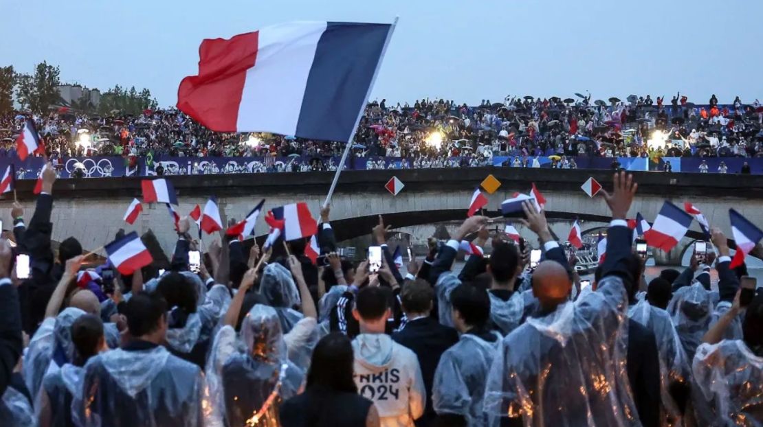 Atletas franceses ondean banderas mientras navegan en un barco por el río Sena durante la ceremonia de apertura de los Juegos Olímpicos de Verano 2024 en París, Francia, el viernes 26 de julio de 2024.