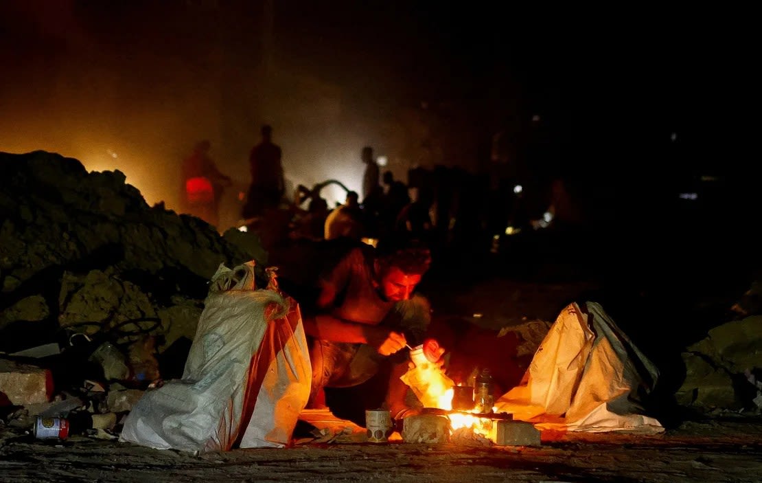 Un hombre en cuclillas junto a un fuego, mientras los palestinos huyen de la parte oriental de Khan Younis, tras las órdenes del ejército israelí de evacuar sus barrios, en Khan Younis, en el sur de Gaza, el 22 de julio de 2024.