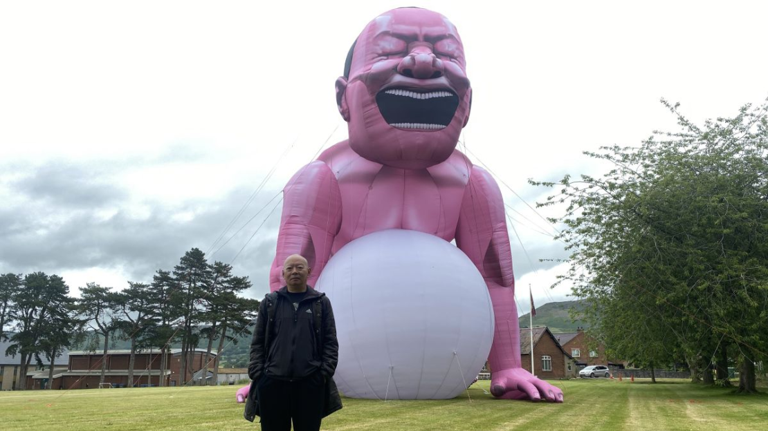 Yue Minjun frente a su instalación de arte inflable (Escuela de Ruthin).