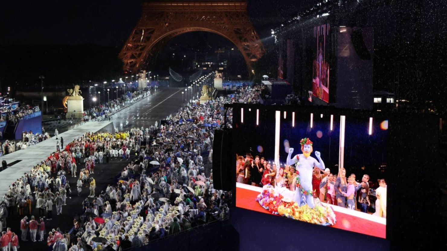 Las delegaciones llegan al Trocadero en París, mientras los espectadores observan al cantante francés Philippe Katerine actuando en una pantalla gigante durante la ceremonia de apertura de los Juegos Olímpicos de París 2024 el 26 de julio.