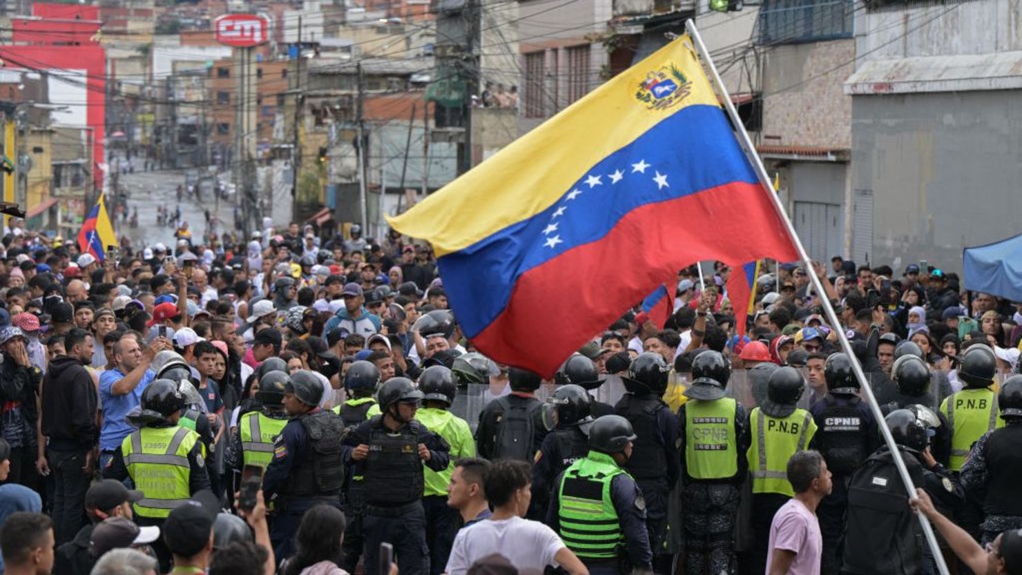 Un hombre agita una bandera venezolana mientras manifestantes chocan con policías durante una protesta contra el gobierno del presidente Nicolás Maduro en Caracas, el 29 de julio de 2024, un día después de las elecciones presidenciales venezolanas. Crédito: YURI CORTEZ/AFP/Getty Images