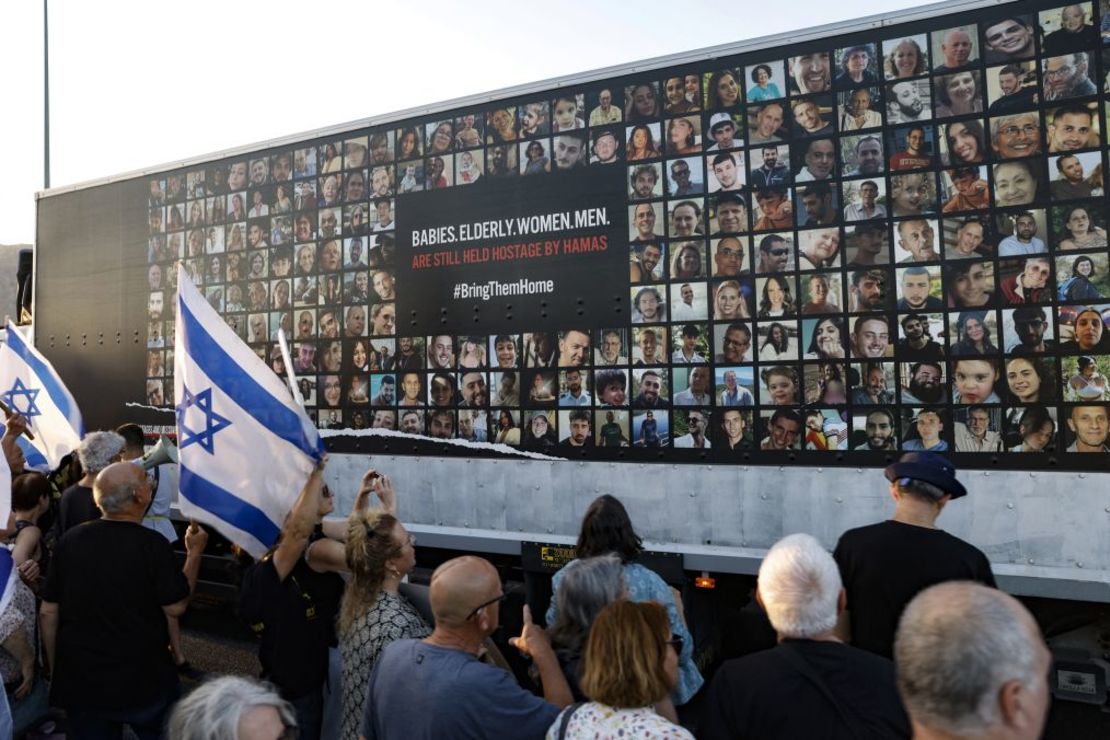 Un grupo de personas junto a un muro cubierto con fotografías de rehenes israelíes retenidos por militantes palestinos de Hamas en Gaza desde los atentados del 7 de octubre, durante una manifestación contra el gobierno israelí, en la ciudad de Karmiel, en el norte de Israel, el 25 de julio. Crédito: Jalaa Marey/AFP/Getty Images