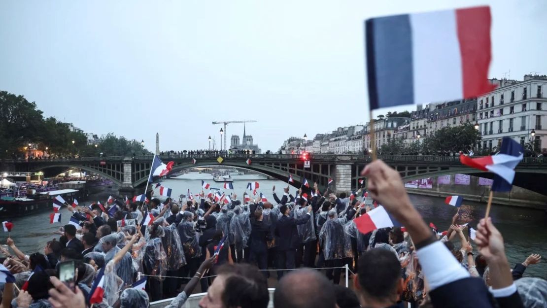 Los atletas franceses agitan banderas mientras navegan en un barco por el río Sena durante la ceremonia de apertura de los Juegos Olímpicos de Verano 2024 en París, Francia, el viernes 26 de julio de 2024.