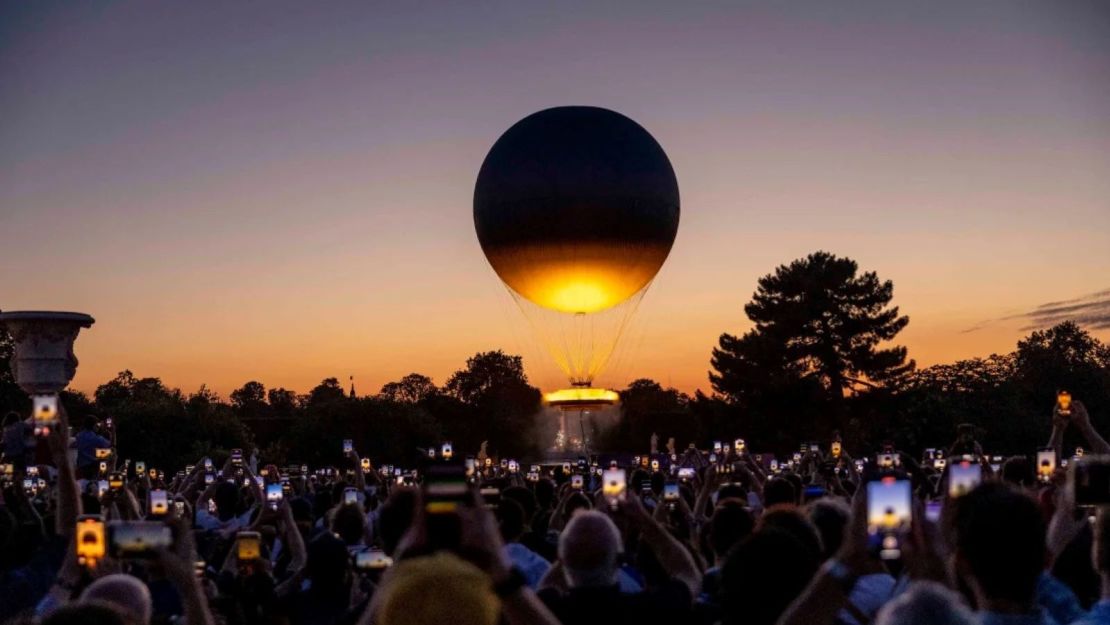 Los visitantes toman fotos del pebetero olímpico mientras se eleva alto después del atardecer en el segundo día de los Juegos Olímpicos de París 2024, el 28 de julio de 2024 en París, Francia.