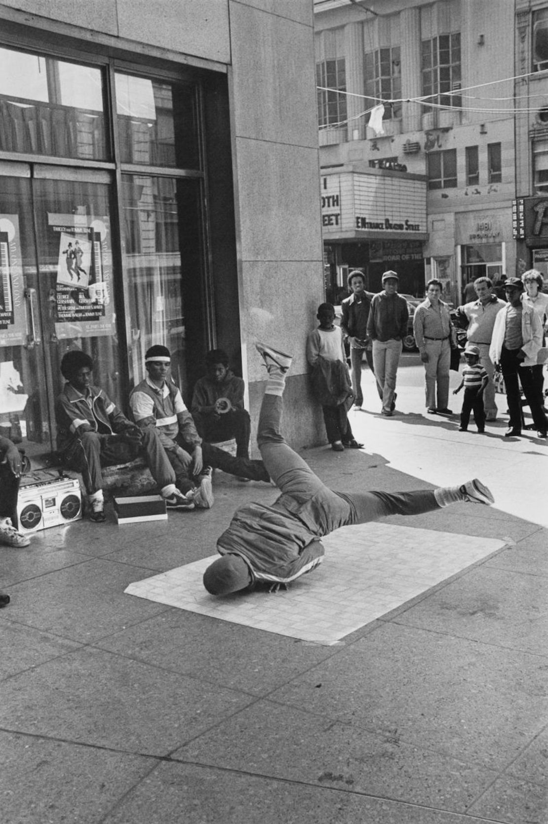 Una multitud se reúne para ver a un joven bailar breakdance sobre un trozo de linóleo en 1980 en Times Square, Nueva York.