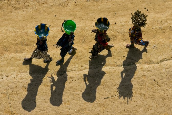 Chicas jóvenes llevando baldes en la región de Dogón, Malí. Durante la temporada seca de África, las mujeres y las niñas a menudo viajan 10 kilómetros a pie para recolectar agua para las tareas del hogar. En África subsahariana, se calcula que esta tarea requiere de hasta 40.000 millones de horas al año (Arthus-Bertrand, Altitudes Anyway).