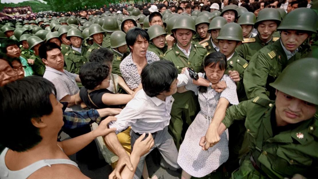 Una joven queda atrapada entre civiles y soldados chinos que intentaban sacarla de una reunión cerca del Gran Salón del Pueblo en Pekín el 3 de junio de 1989.