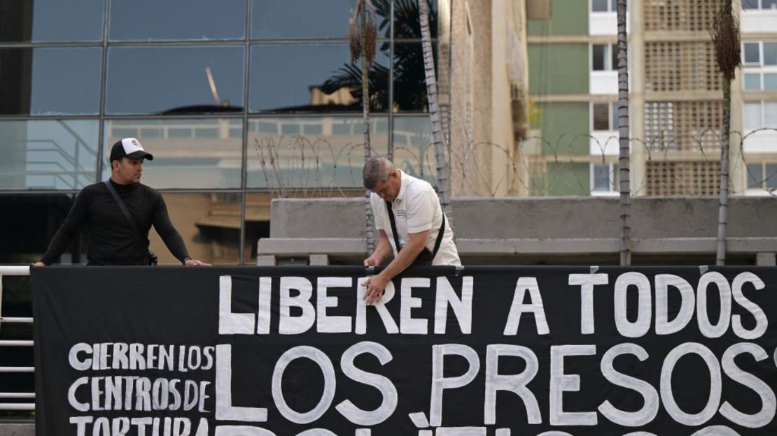 Un hombre cuelga una pancarta exigiendo la libertad de los presos políticos detenidos durante las protestas tras la impugnada reelección del presidente venezolano Nicolás Maduro, durante una vigilia convocada por la oposición en Caracas, el 8 de agosto de 2024.