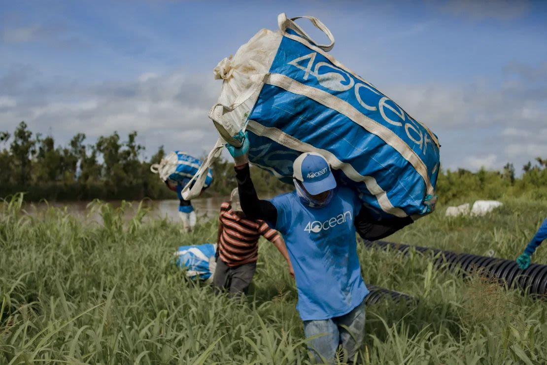 Los empleados locales recogen la basura en grandes bolsas azules.