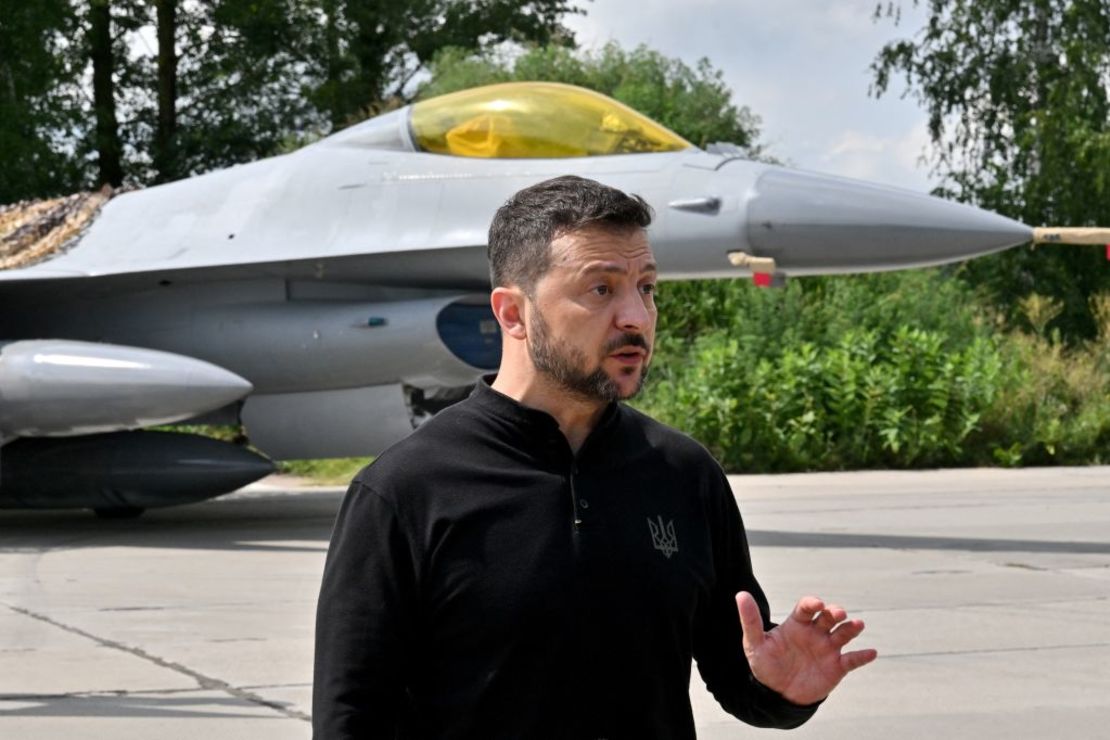 El presidente de Ucrania, Volodymyr Zelensky, habla con medios de comunicación mientras está de pie frente a un avión de combate F16 durante el Día de las Fuerzas Aéreas de Ucrania el 4 de agosto de 2024.