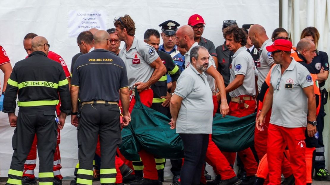 El personal de rescate transporta una bolsa para cadáveres a tierra mientras prosigue la búsqueda del superyate naufragado Bayesian.