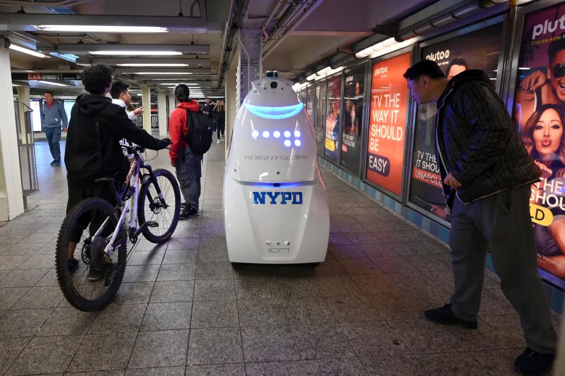 Un grupo de viajeros observa el robot autónomo de seguridad Knightscope K5 de la Policía de Nueva York en la estación de metro de Times Square, en Nueva York.