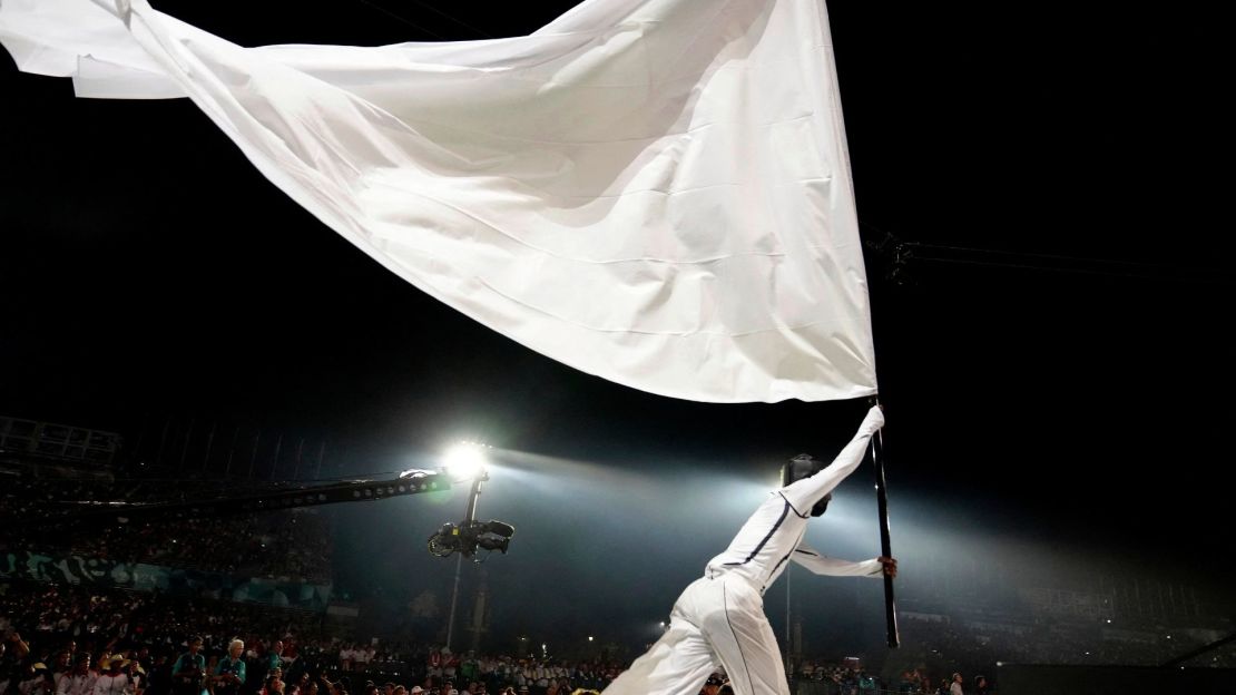 Un artista ondea una bandera blanca gigante en la Plaza de la Concordia durante la ceremonia de inauguración de los Juegos Paralímpicos de París 2024