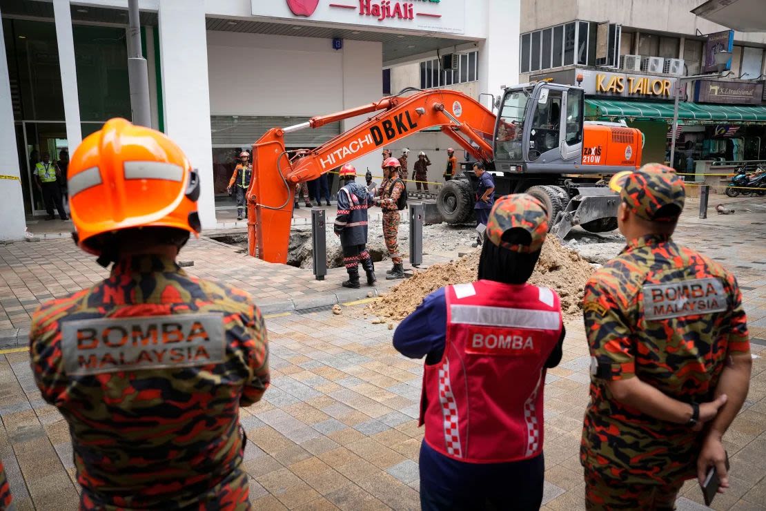 Trabajadores del Departamento de Bomberos y Rescate buscan a una mujer que cayó en un socavón después de que una sección de la acera se derrumbara en Kuala Lumpur el 23 de agosto de 2024. Crédito: Vincent Thian/AP