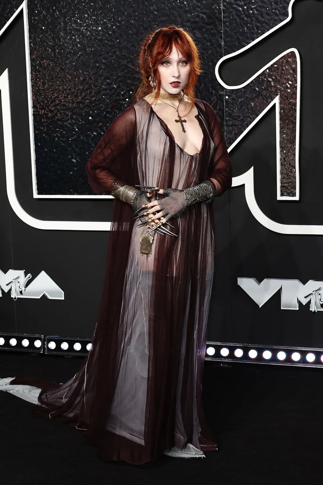 Chappell Roan paired his gothic-inspired Y/Project dress with a gorgeous cross and some dramatic pieces made out of gloves. Image credit: Jamie McCarthy/WireImage/Getty Images.