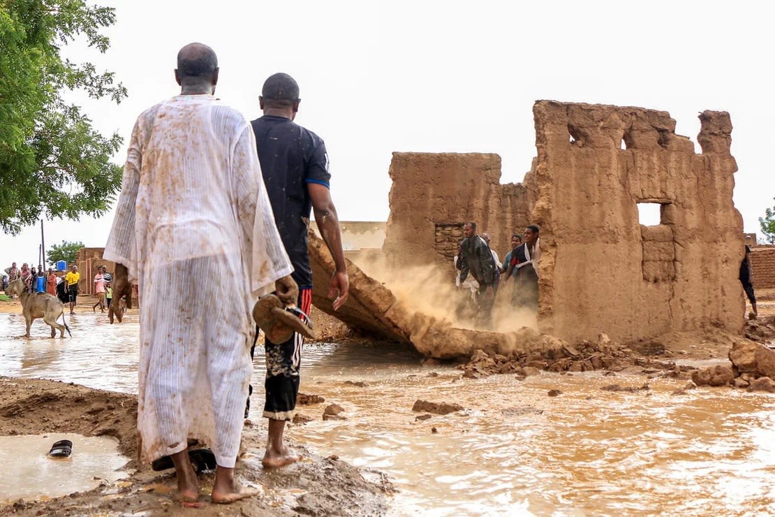 Los hombres derriban el muro de adobe de una casa para que actúe como dique improvisado en medio de las inundaciones en el área de Messawi, cerca de Meroe, en el estado norteño de Sudán, el 27 de agosto de 2024.