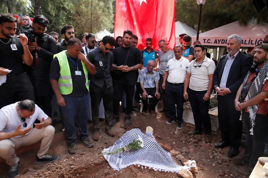 Mehmet Suat Eygi, padre de la activista turco-estadounidense Aysenur Ezgi Eygi, reza con familiares y amigos junto a su tumba.