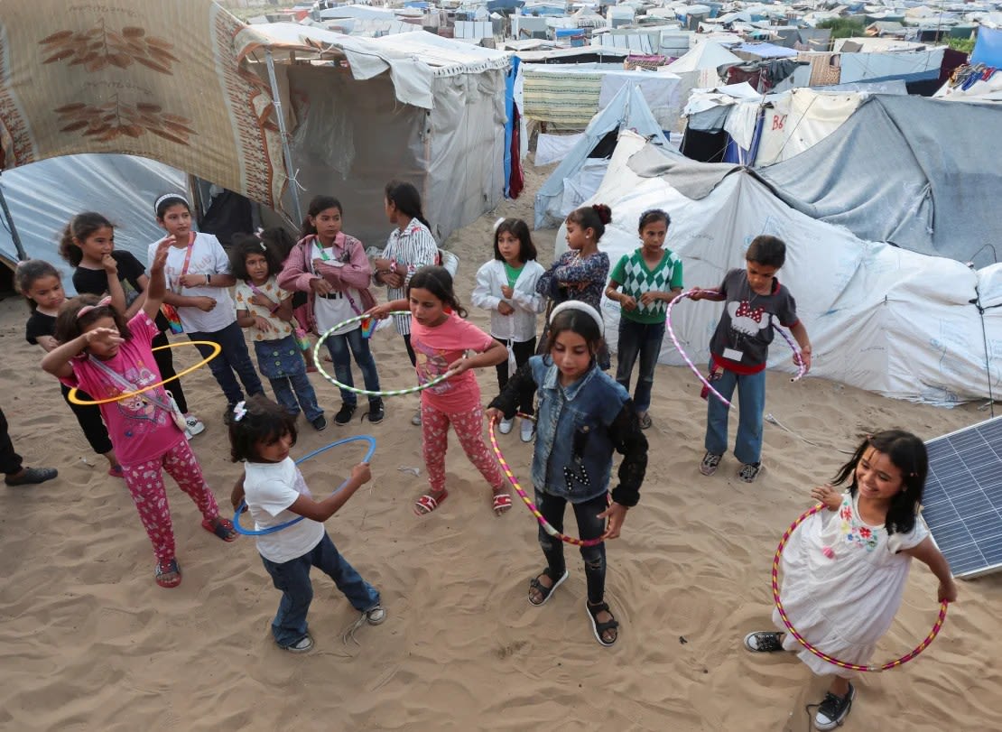 Niños palestinos juegan con aros de hula hula cerca de un campamento de tiendas de campaña improvisado mientras las escuelas permanecen cerradas debido a la ofensiva militar de Israel, en Deir Al-Balah, en el centro de Gaza, el 28 de abril.