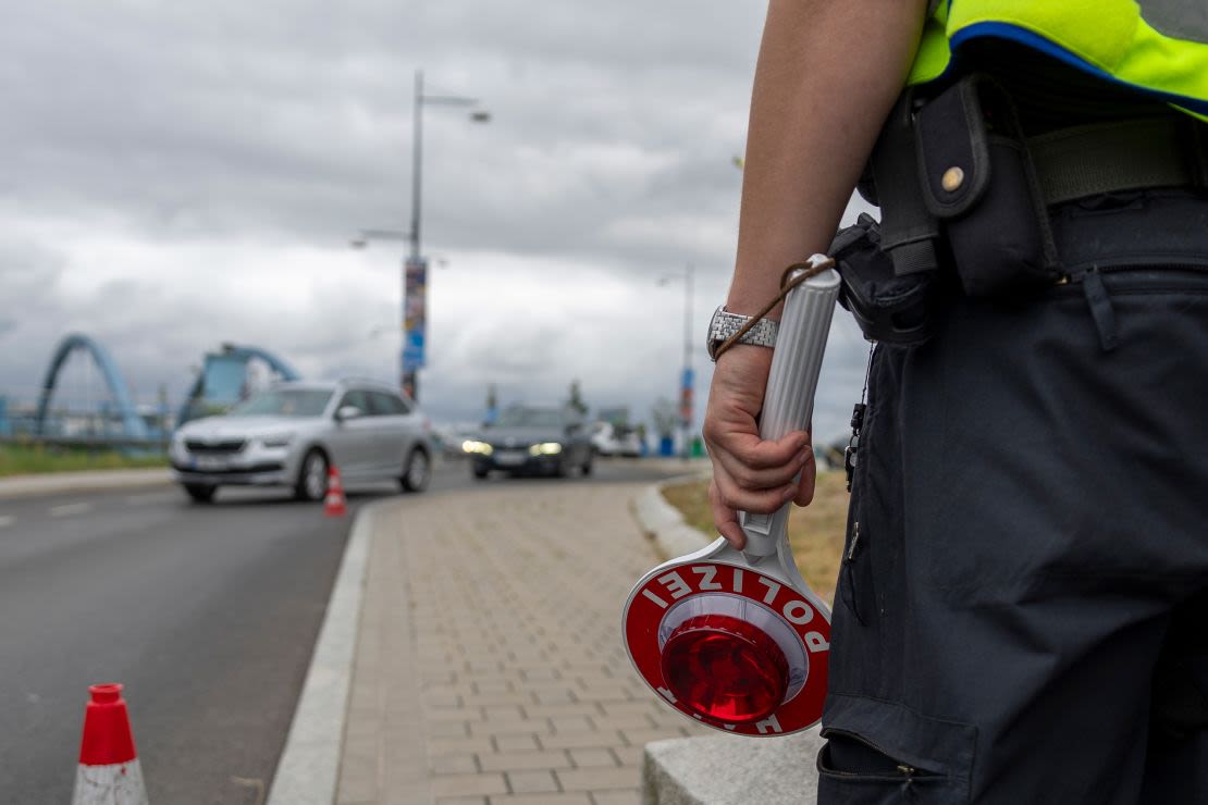 Un policía alemán sostiene un cartel de "Alto, policía" mientras vigila los coches que llegan a la frontera germano-polaca.