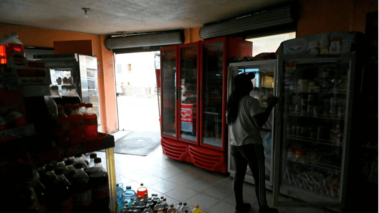 Una mujer se encuentra dentro de una tienda oscura debido al racionamiento de energía en Quito, el 18 de abril de 2024.