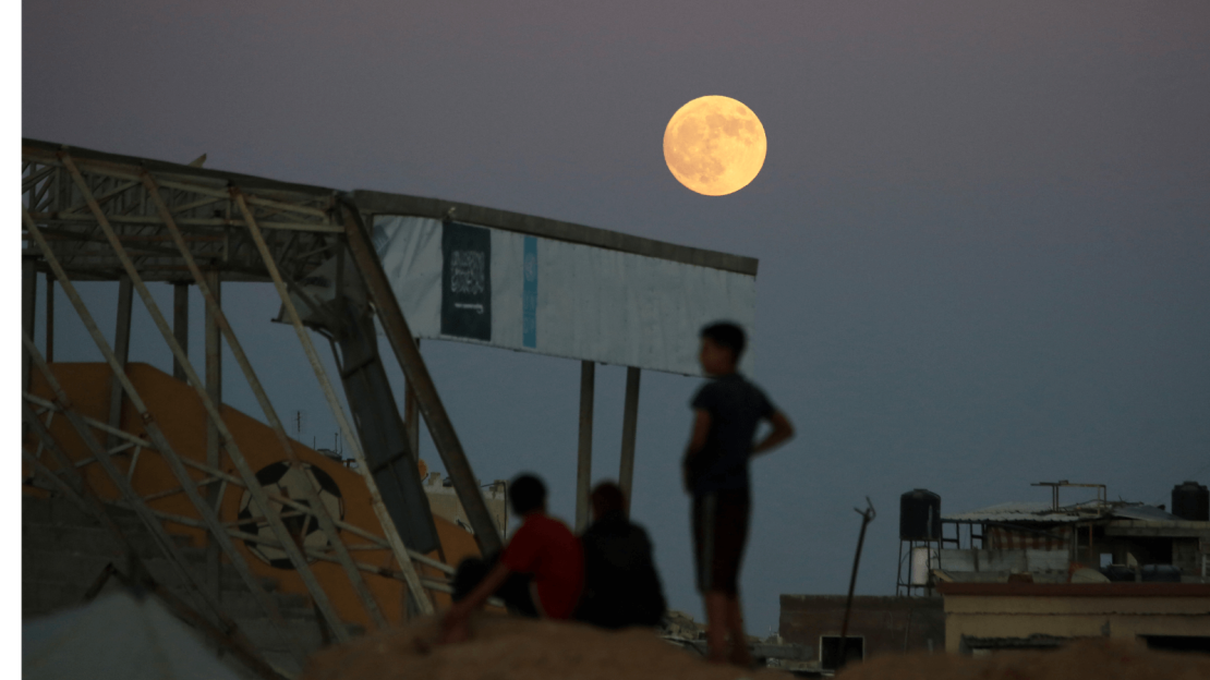 Jóvenes palestinos observan cómo la luna llena se eleva sobre Khan Yunis en el sur de Gaza el 17 de septiembre de 2024 en medio de la guerra en curso en el territorio palestino entre Israel y Hamas.