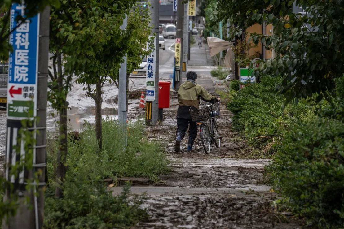 Un hombre empuja su bicicleta por una acera fangosa luego de una fuerte lluvia en la ciudad de Wajima, el 22 de septiembre de 2024. Crédito: Yuichi Yamazaki/AFP/Getty Images.