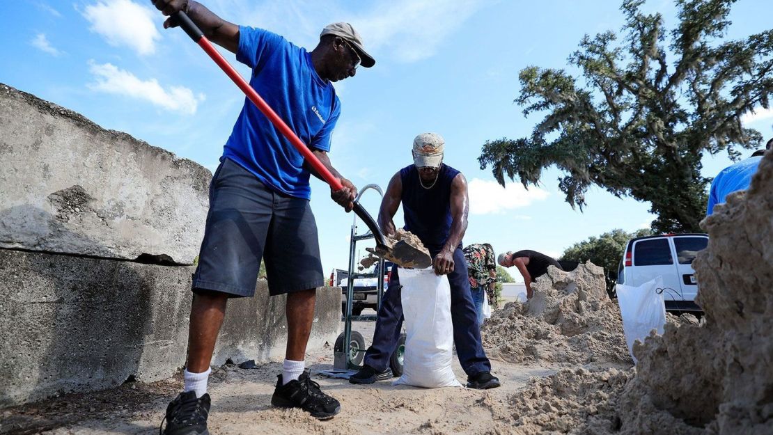 Herman Mccrimager pala arena para llenar bolsas con su amigo Connell Crooms el martes 24 de septiembre en Woerner Turf and Landscaping Supply en Jacksonville, Florida.