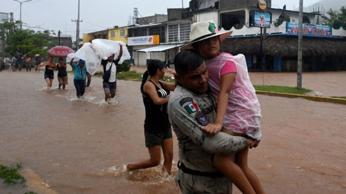 Un miembro de la Guardia Nacional ayuda a una niña en una calle inundada después del impacto del huracán John en Acapulco, México, el 26 de septiembre de 2024.