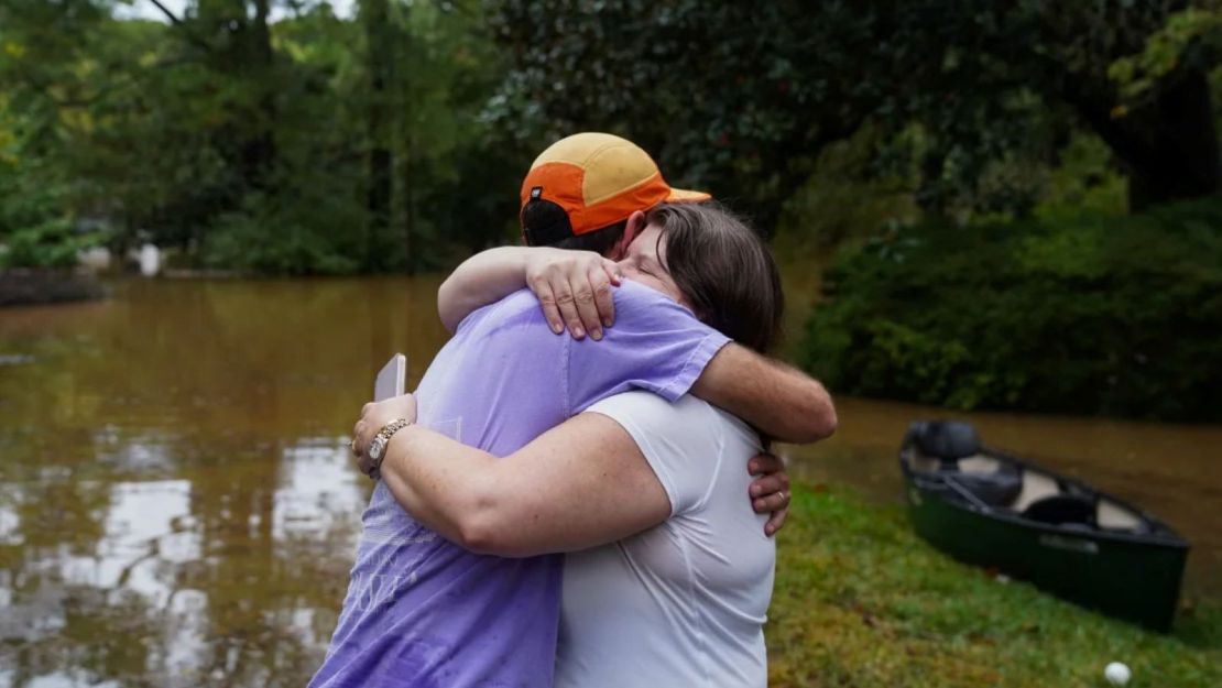 Dan Murphy abraza a su colega después de llevar su canoa para rescatarlos de su casa inundada, ya que las calles están anegadas cerca de Peachtree Creek, el 27 de septiembre de 2024 en Atlanta, Georgia.