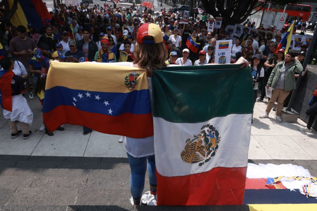 Una mujer sostiene las banderas de Venezuela y México en una manifestación en Ciudad de México a dos meses de las elecciones presidenciales en Venezuela