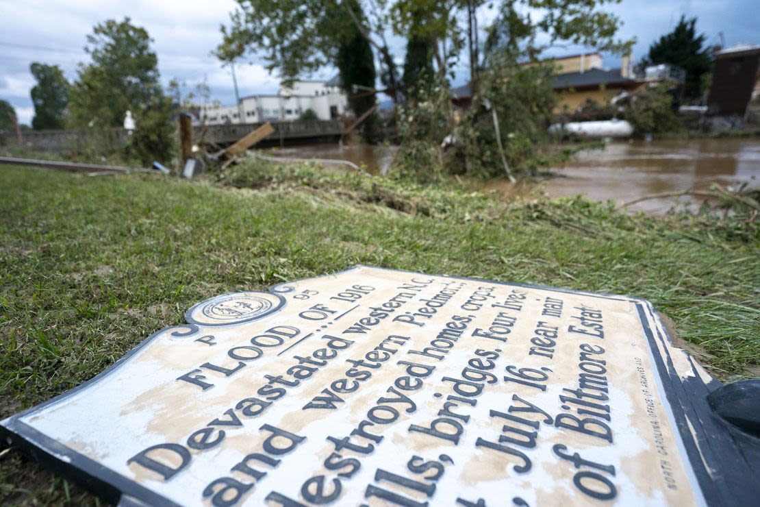 Un cartel conmemorativo de la inundación de 1916 yace en el suelo junto a una vía fluvial inundada cerca de Biltmore Village. Crédito: Sean Rayford/Getty Images