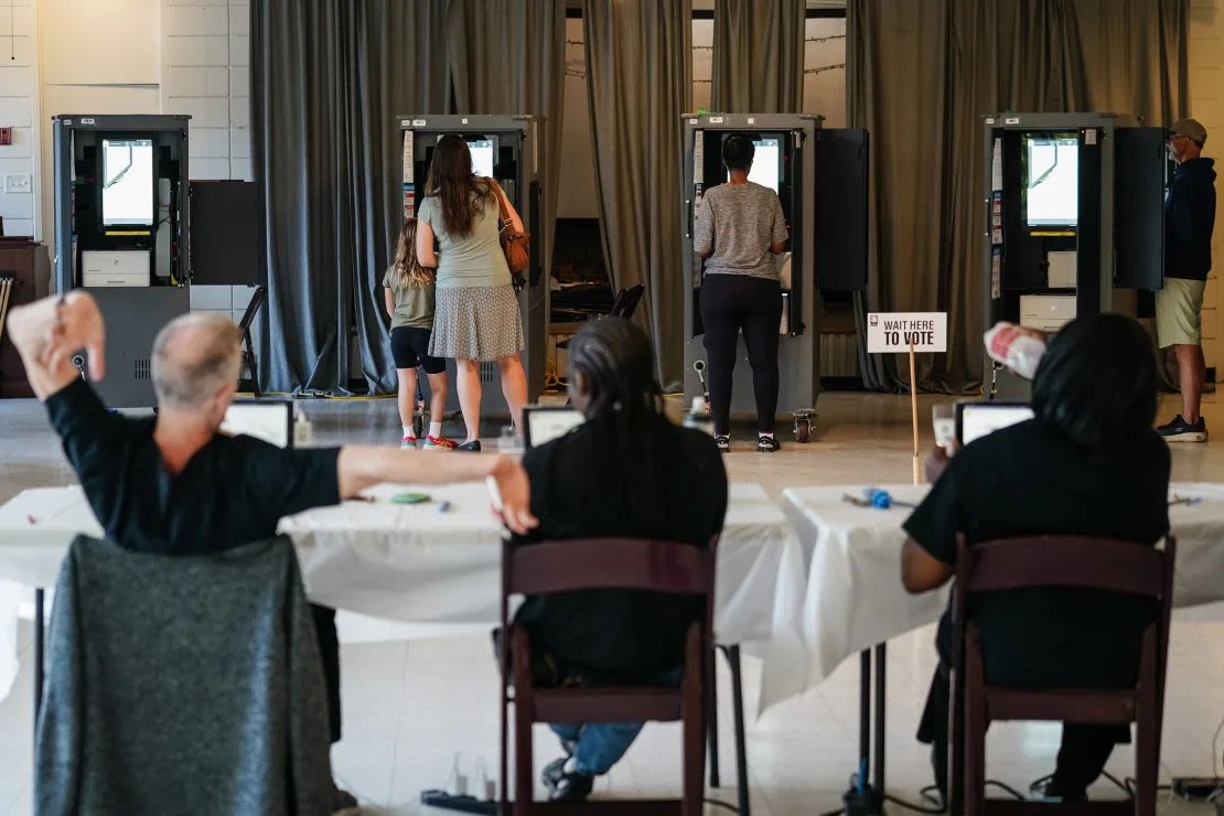 Un trabajador de las elecciones del condado de Fulton estira sus brazos mientras los votantes emiten sus votos en la elección primaria de Georgia en un centro de votación en Atlanta el 21 de mayo de 2024.