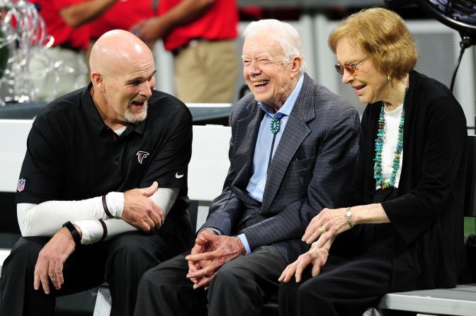 Los Carter conversan con el entrenador en jefe de los Atlanta Falcons, Dan Quinn, antes de un partido de la NFL en septiembre de 2018.