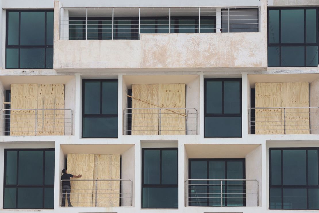 Un hombre en Progreso cierra con tablones un edificio de apartamentos para protegerlo del huracán Milton el lunes.