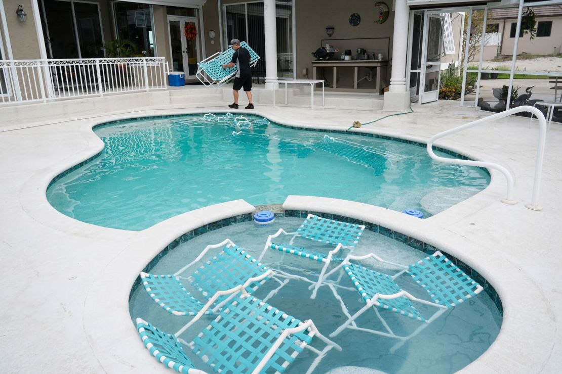 David Jalving arroja muebles de exterior a la piscina de su padre en Fort Myers para prepararse para el huracán Milton.