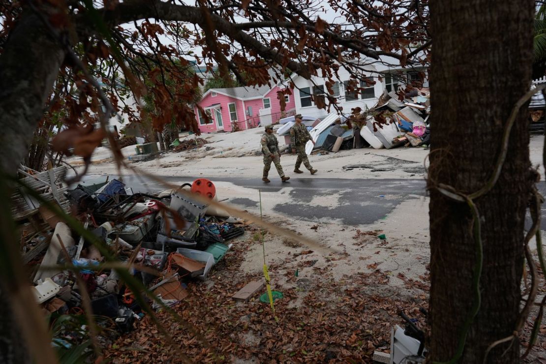 Miembros de la Guardia Nacional del Ejército de Florida revisan el martes si quedan residentes en la casi desierta Bradenton Beach. A su alrededor, todavía hay montones de escombros del huracán Helene afuera de las casas dañadas.