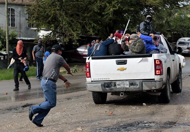 Un hombre lanza objetos contra presuntos estudiantes de la escuela de Ayotzinapa. El incidente se registró cerca de un centro de votación en Tixtla, Guerrero.