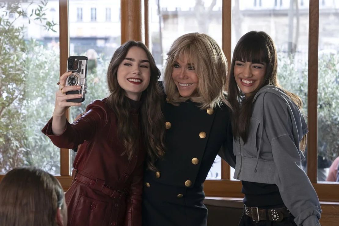 Brigitte Macron (centro) apareció en un episodio donde posó para una selfie con Lily Collins como Emily (izquierda) y Thalia Besson como Genevieve (derecha). Crédito: Netflix.