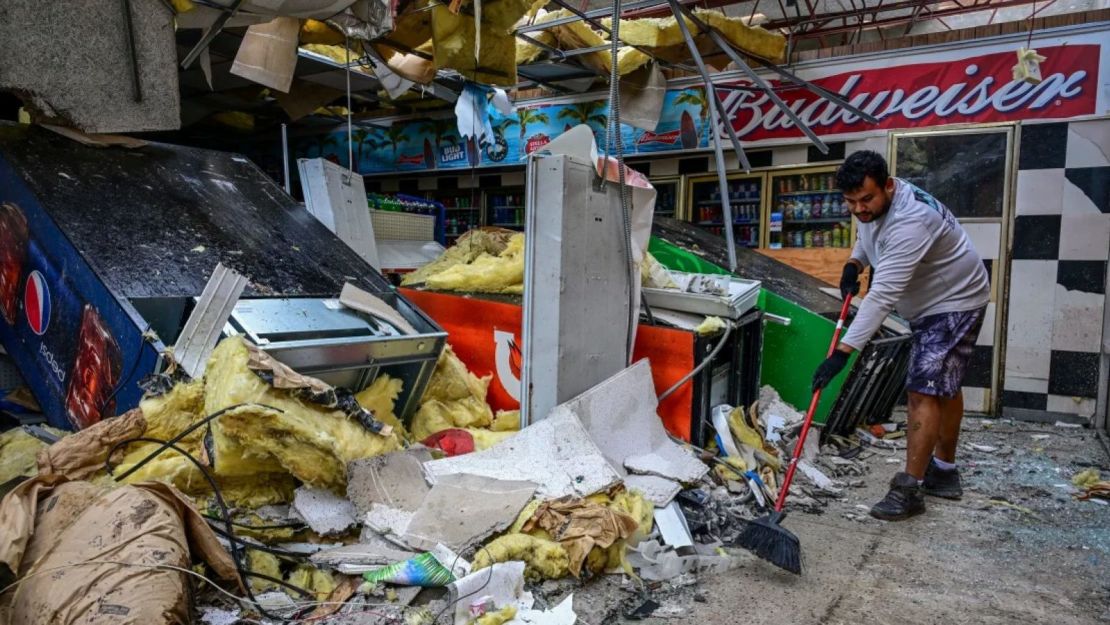 Un hombre limpia los escombros dentro de una tienda de una gasolinera en Lakewood Park, Florida, después de que un tornado golpeara el área mientras el huracán Milton atravesaba la región el 10 de octubre de 2024.