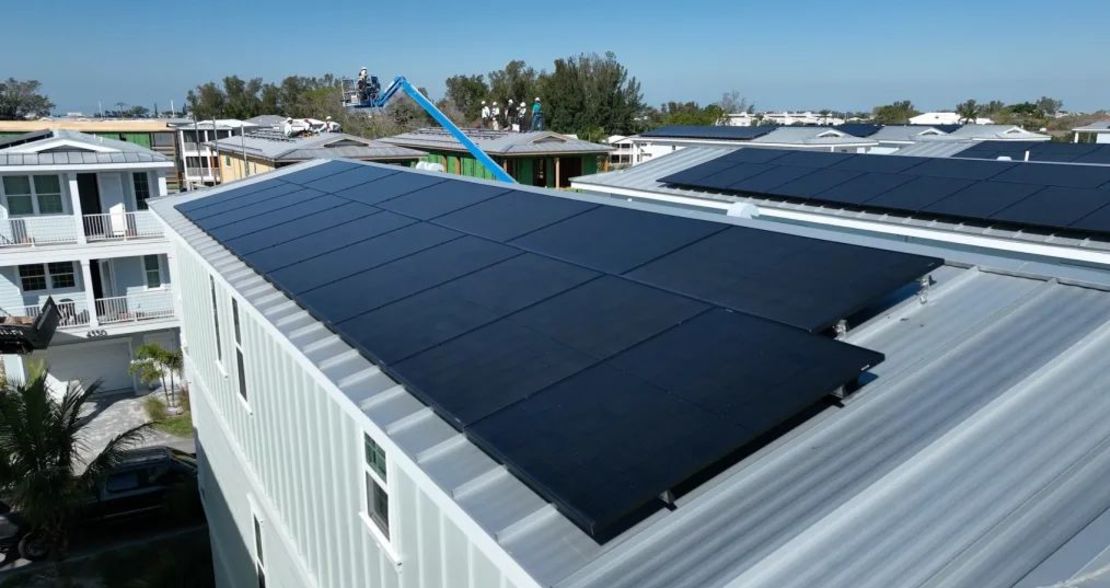 Trabajadores fijando paneles solares a las juntas verticales elevadas de los tejados para evitar que salgan volando durante las violentas tormentas de abril de 2024.