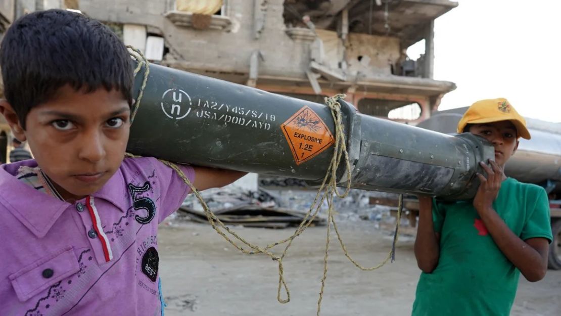 Niños palestinos transportan un contenedor de munición estadounidense vacío en Khan Younis, en el sur de Gaza, el 16 de mayo de 2024.