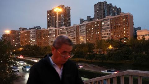 Un hombre camina por un puente peatonal frente a edificios residenciales en Beijing, China, el 16 de octubre de 2024.