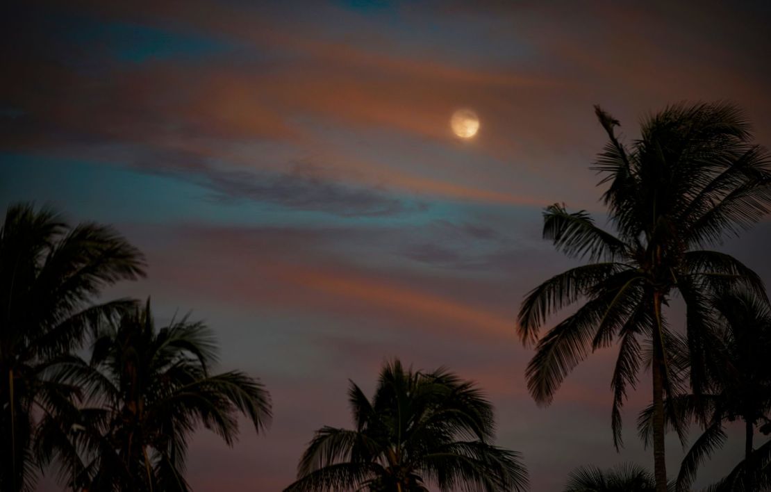 La luna, en su fase gibosa creciente, asoma entre las nubes en el muelle de Nápoles, Florida, este martes.