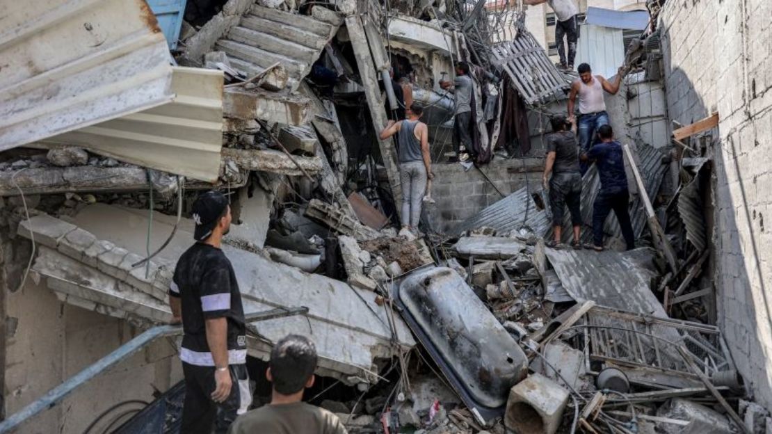 Personas se reúnen fuera de un edificio derrumbado mientras intentan sacar a un hombre de entre los escombros tras un bombardeo israelí en Jabalia, en el norte de la Franja de Gaza, el 15 de octubre de 2024.