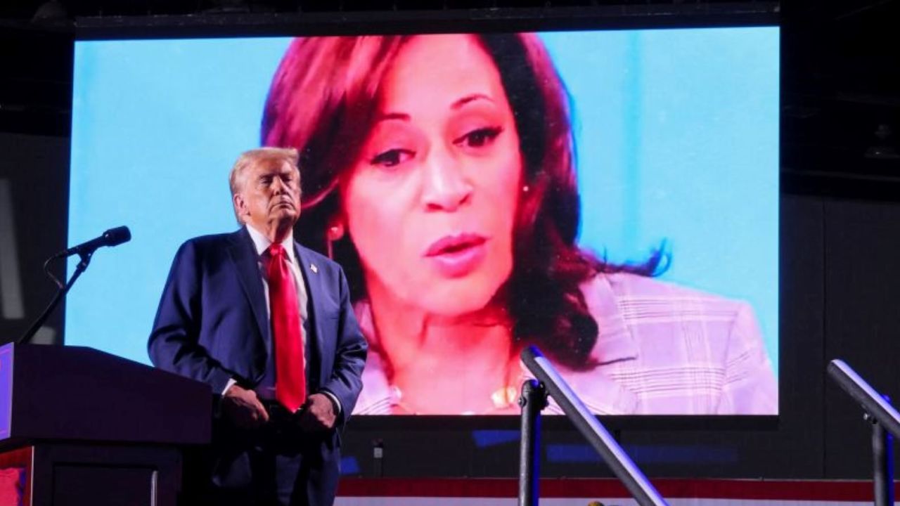 El expresidente Donald Trump observa mientras el rostro de la vicepresidenta Kamala Harris aparece en una pantalla mientras se reproduce un video durante su mitin en Detroit el 18 de octubre de 2024.