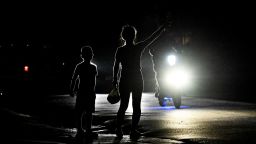 Una mujer con su hijo hace señales a un automóvil en una calle oscura durante un apagón en el municipio de Bauta, provincia de Artemisa, Cuba, el 18 de marzo de 2024. Fotografía de archivo